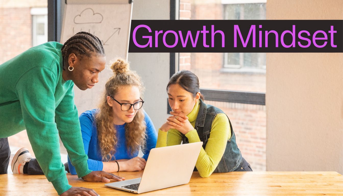 A diverse group of three young professionals collaborating on a laptop project in a bright office environment.