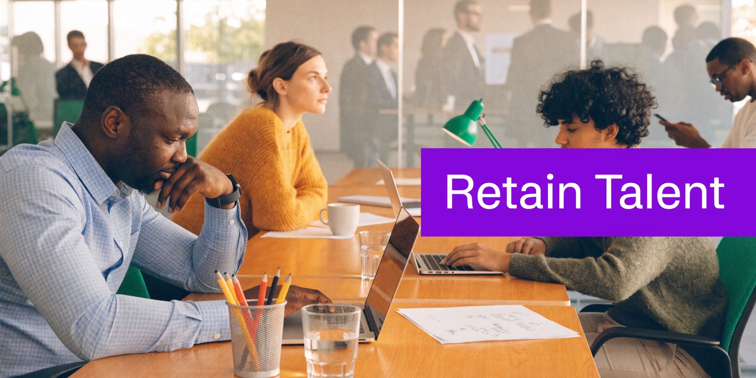 A diverse group of professionals working in a modern office, focusing on retaining talent and employee engagement.