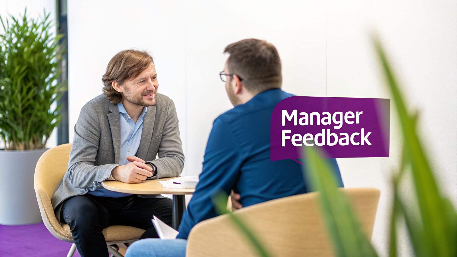 Two men in a modern office meeting, discussing with 'Manager Feedback' text overlay.