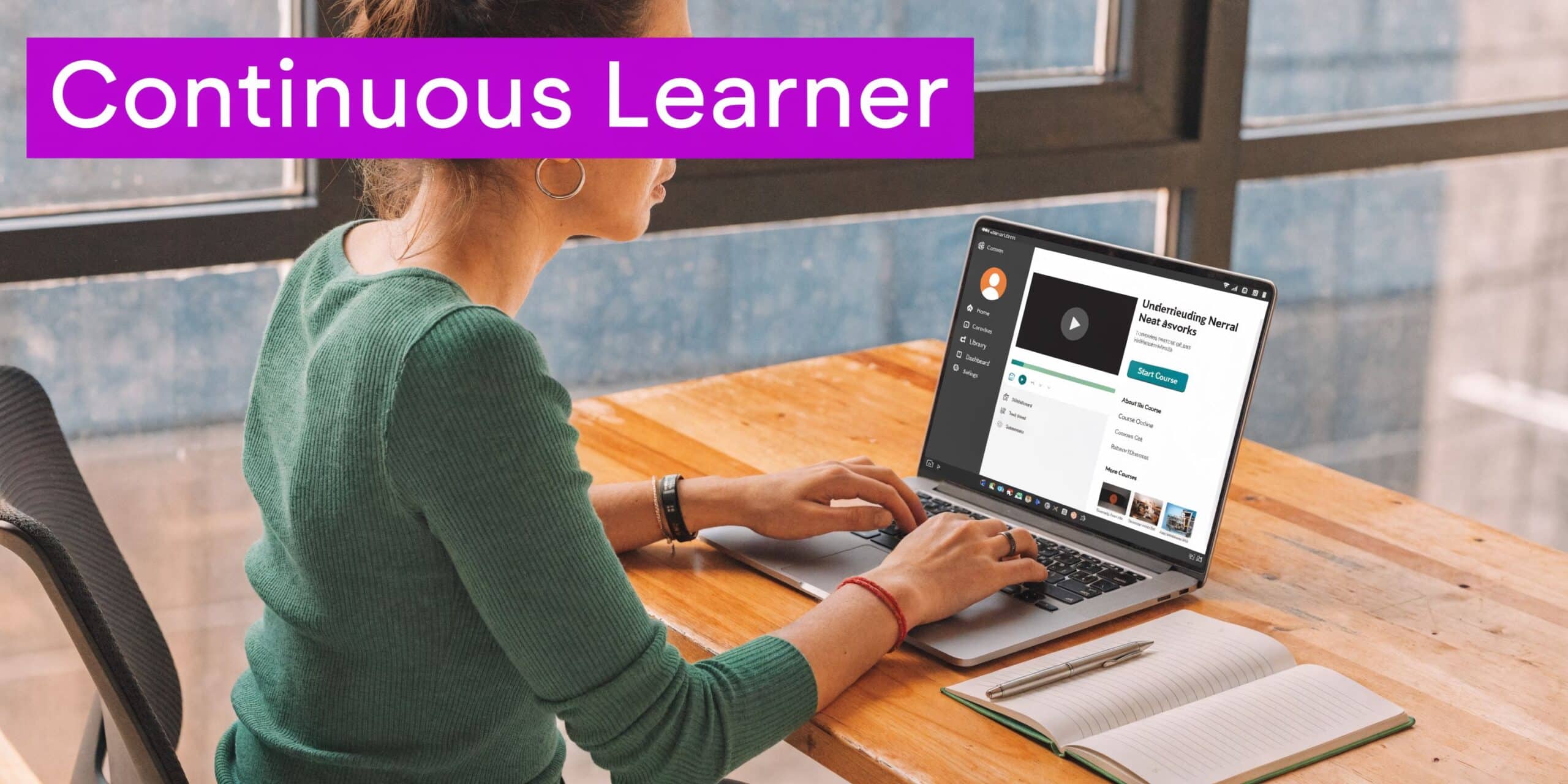 A woman studying online on her laptop at a desk with an open notebook nearby.