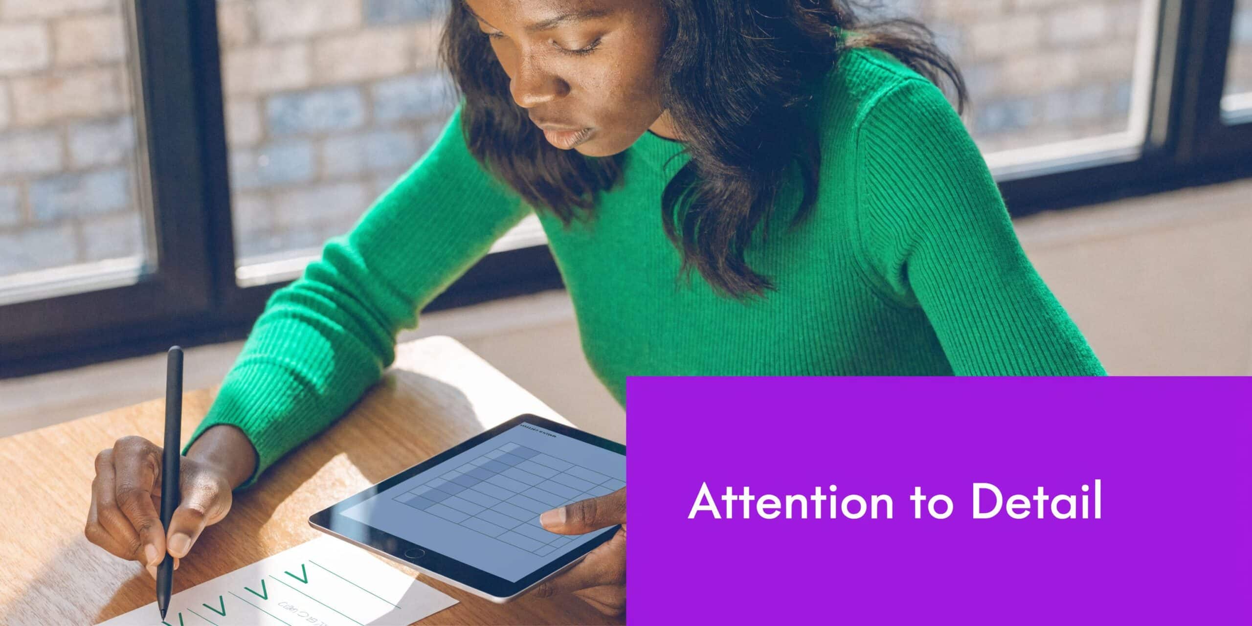 A professional woman in a green top focuses on her work using a digital tablet and pen.