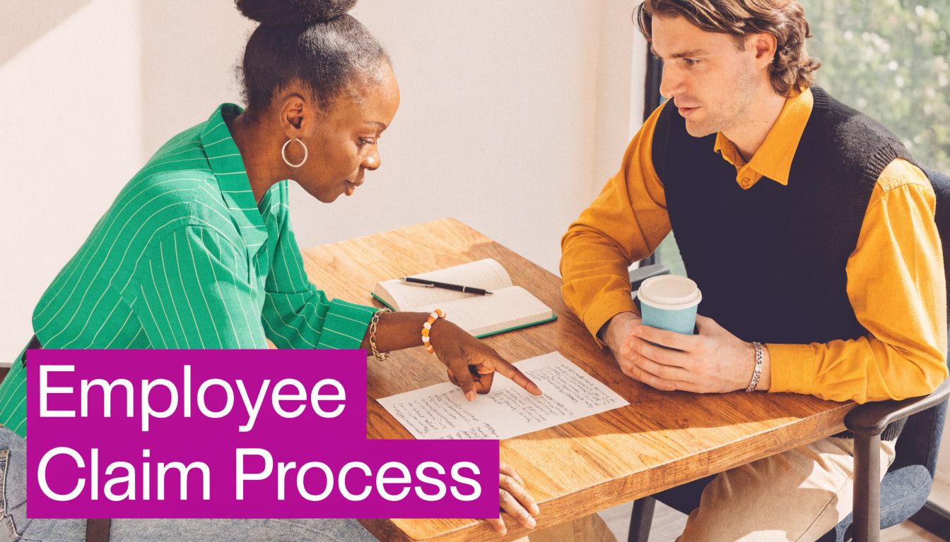 A woman and a man reviewing documents at a table during an employee claim process discussion.