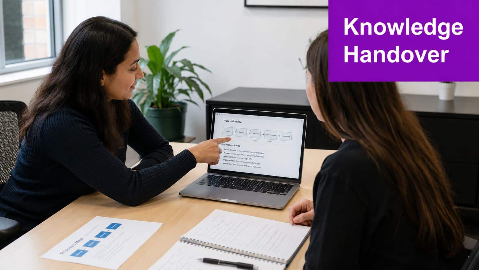 Two colleagues sitting at a desk reviewing a business process workflow on a laptop screen.